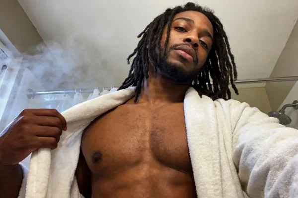 Black man with dreadlocks taking a selfie in a bathrobe