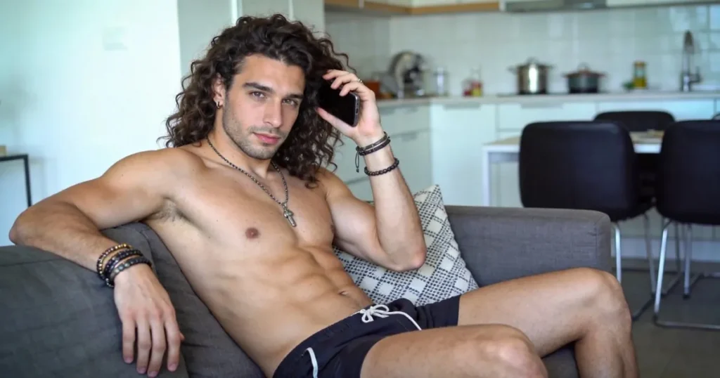 Curly-haired man relaxing on a sofa with his phone