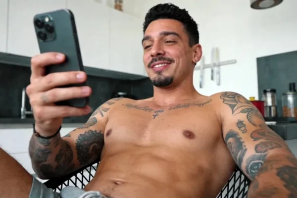 Tattooed man smiling while chatting on his phone
