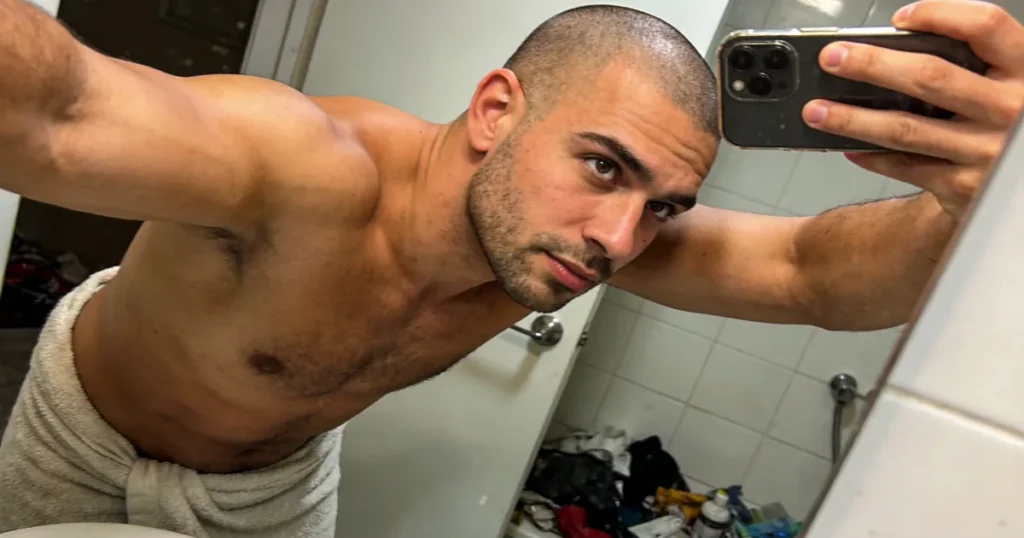 Shirtless man taking a mirror selfie with his phone