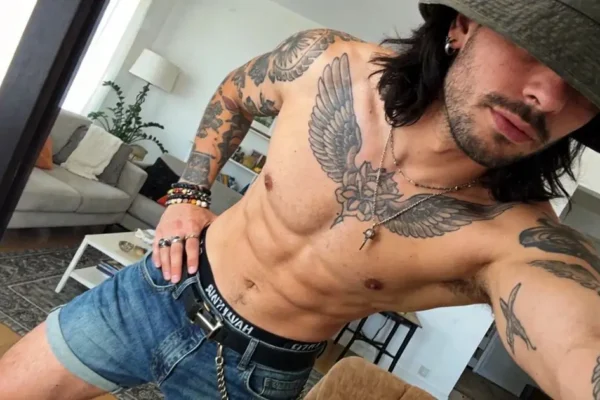 shirtless man wearing a bucket hat and taking a mirror selfie for anonymous gay chat